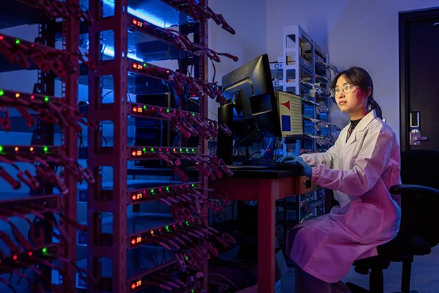 Female student wearing a lab coat working in front of computer