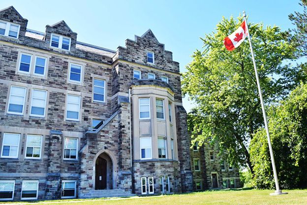 Western campus building with Canadian flag on flag pole out front.